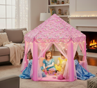 A young girls smiling and role playing as  princesses inside a pink unicorn-themed princess play tent with star LED lights.